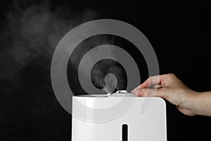 Woman using modern air humidifier on background, closeup