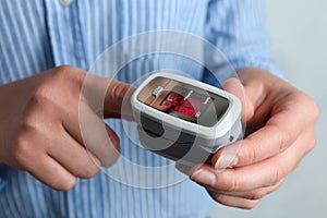 Woman using modern fingertip pulse oximeter on background, closeup