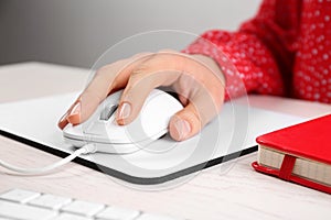 Woman using modern optical mouse at office table, closeup