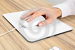 Woman using modern wired optical mouse at table, closeup