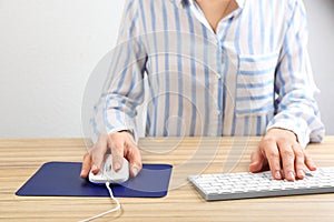 Woman using modern wired optical mouse at table, closeup