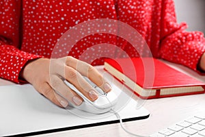 Woman using modern wired optical mouse at office table