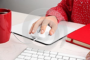 Woman using modern wired optical mouse at office table