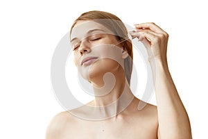 Woman using moisturized serum to make her skin firmer and softer against white studio background. Self-care routine