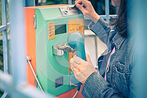 Woman using old and weathered oldstyle plublic pay phone in phone booth