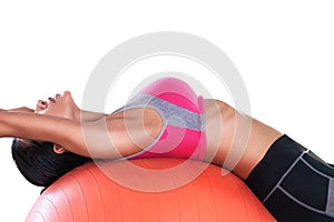 Woman using orange fitness ball to strech her back and exercise her abs isolated on white background