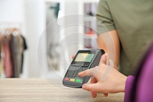 Woman using payment terminal in shop. Space for text