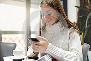 Woman using phone and drinking coffee.