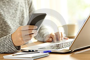 Woman using a phone and a laptop on a table photo
