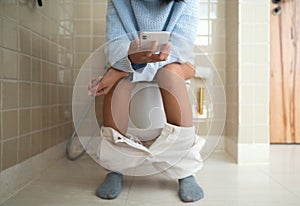 Woman using phone while using the bathroom