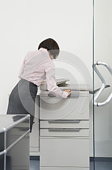 Woman Using Photocopier In Office