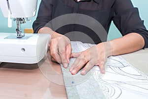 Woman is using pin holding fabric sewing machine for sewing bed sheet