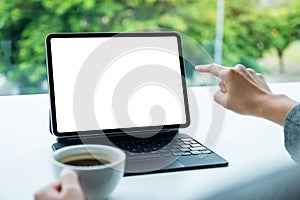 A woman using and pointing finger at digital tablet with blank desktop white screen as a computer pc in office