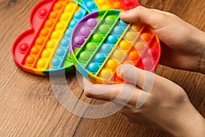 Woman using pop it fidget toy at wooden table, closeup photo