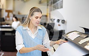 Woman using printer while working in print shop