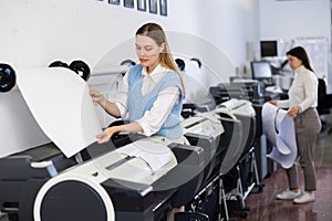 Woman using printer while working in print shop