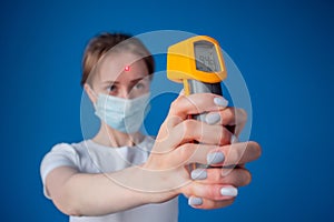 Woman using pyrometer to measure body temperature, blurred background