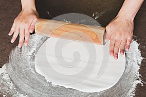 Woman using rolling pin preparing royal icing for cake decorating