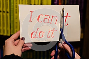 Woman using scissors to remove the word can`t to read I can do it