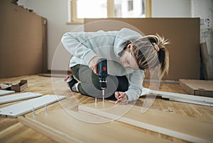 Woman using screwdriver for assembling furniture