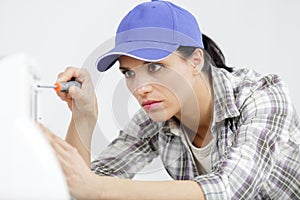woman using screwdriver to repair appliance
