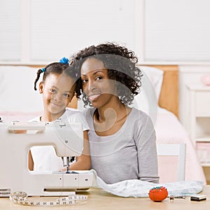 Woman using sewing machine with daughter