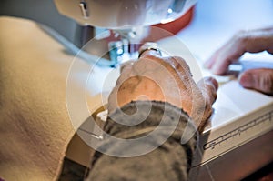 Woman using sewing machine, detail on the hands