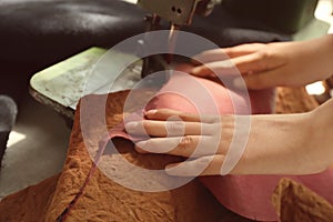 Woman using sewing machine in leather workshop