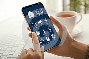 Woman using Smart Home app on mobile phone indoors, closeup