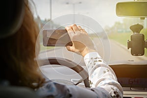 Woman using smart phone camera while driving the car