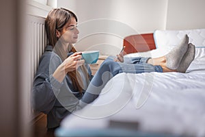 Woman using smart phone, drinking coffee and relaxing at home