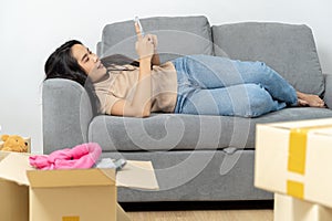 Woman using Smart phone for moving to college, leaving apartment ready for movers pick up with package of cardboard boxes for