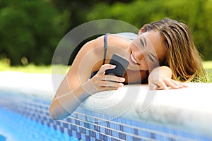 Woman using a smart phone in a poolside in summer