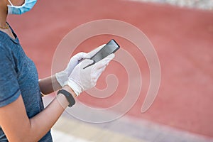 Woman using phone with protective gloves and mask
