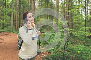 Woman using smart phone while walking through the forest