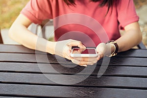 Woman using smartphone for the application on table in park cafe.