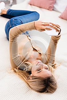 Woman using smartphone on bed at