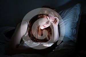Woman using smartphone in bed late at night in bed