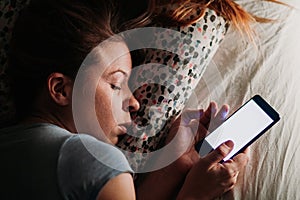 Woman using smartphone in bed at night