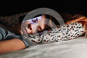 Woman using smartphone in bed at night