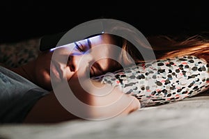 Woman using smartphone in bed at night