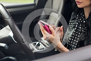 Woman using smartphone. Blurred car interior