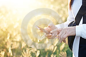 Woman using smartphone in field grass on sunset