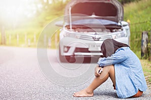 Woman using smartphone in front of her broken car on the road. C