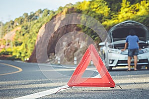 Woman using smartphone in front of her broken car on the road. C