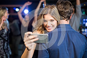 Woman using smartphone while hugging boyfriend