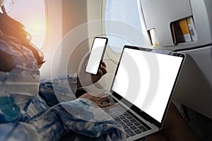 Woman using smartphone and laptop. Travel and aviation technology uses smartphones while sitting in a plane