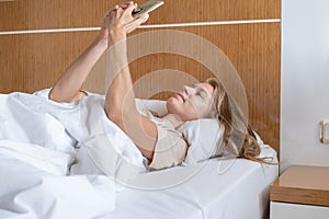 Woman using smartphone lying in bed
