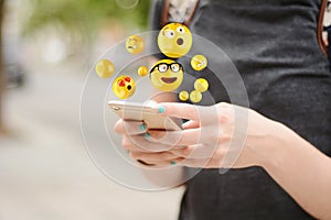 Woman using smartphone sending emojis.