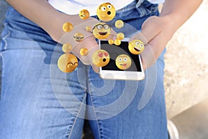 Woman using smartphone sending emojis.
